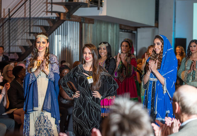 Muska Haseeb, a refugee from Afghanistan, fashion designer, and new US citizen, poses with models wearing her designs at HOPE Couture.