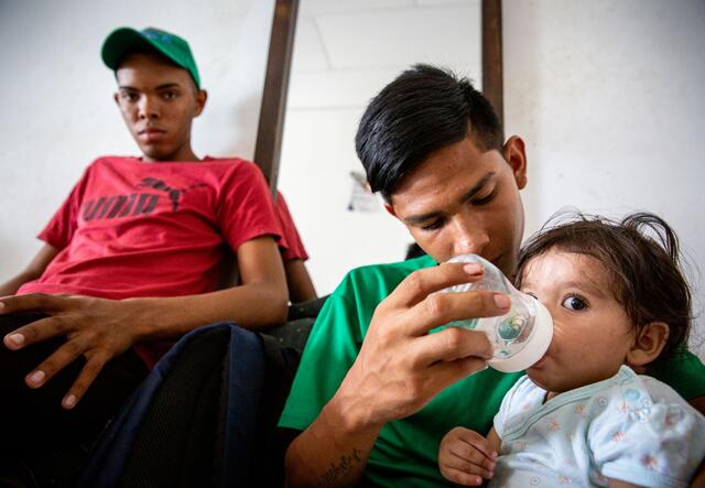 A baby is bottle-fed by her 15-year-old cousin, a Venezuelan refugee in Colombia. The family was supported by the IRC.