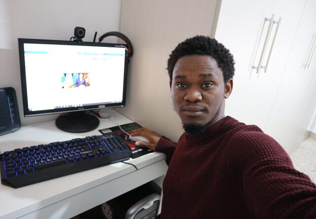 Henry, a Refugee.Info moderator, poses in front of his computer while sharing vital information with refugees and asylum seekers in Italy. 