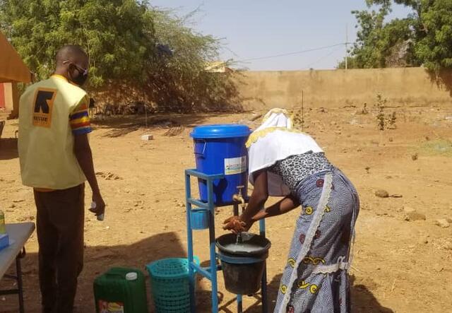 A woman washes her hands while an IRC staff member looks on in Burkina Faso