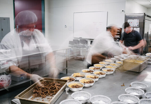 In motion photo of Spice Kitchen chefs preparing meals in a kitchen.