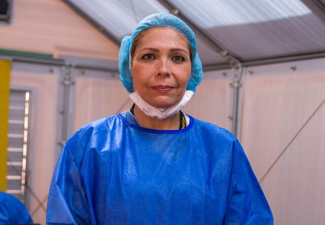 Dr. Eda Patricia Gomez, wearing bright blue scrubs and looking straight at the camera. 