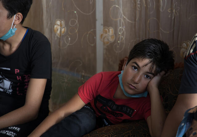 Nine-year-old Ahmad sits and looks at the camera with his head in his hand. 