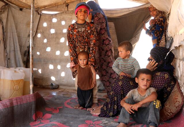 A family sits inside their tent in Syria after being displaced by violence.