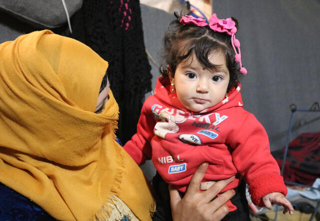 Um Tamer cradles her daughter Zainab in her tent in Areesha refugee camp in Syria.