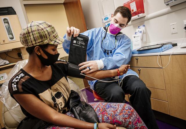 A dental worker takes the blood pressure of a woman at the dentist office