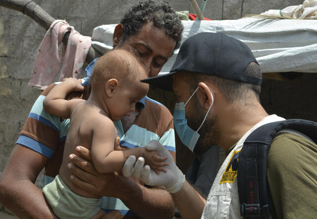 An IRC mobile health worker examines Thabit's baby son for signs of malnutrition