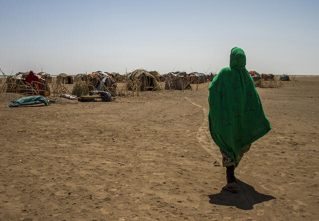 A woman looks into the distance at the temporary shelter in a refugee camp in Ethiopia. 