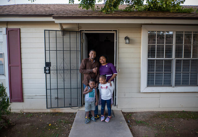 Congolese refugees Robert and Esther pose for a photo with their two young children at the front  door of their home in Phoenix.