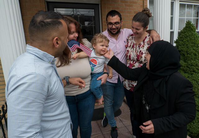 Maha al-Obaidi, a refugee from Iraq, interacts with her grandson in his mother's arms.