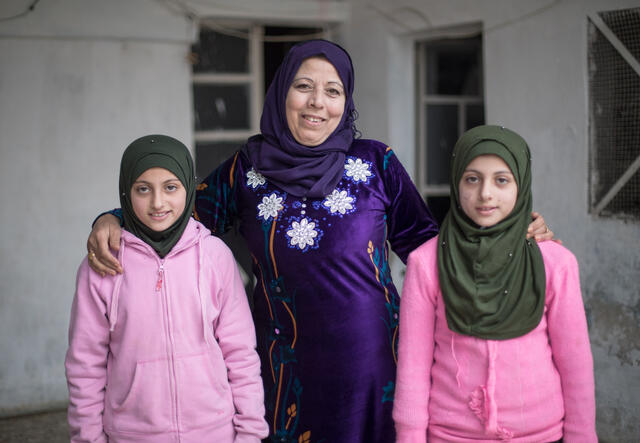 Reema stands between her twins Shurouq and Shirina with her arms around them.