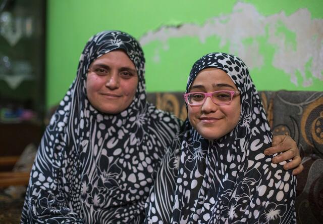 Wearing matching outfits, Ruba and her daughter Salam sit next to one another. 