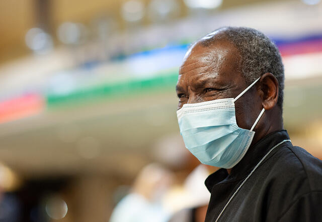 A close up of Patrice at the airport waiting for his daughter. He is wearing a mask. 