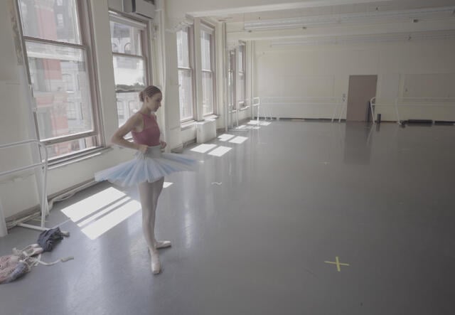 Ballerina Christine Shevchenko, wearing a tutu, stands poised to rehearse in a dance studio