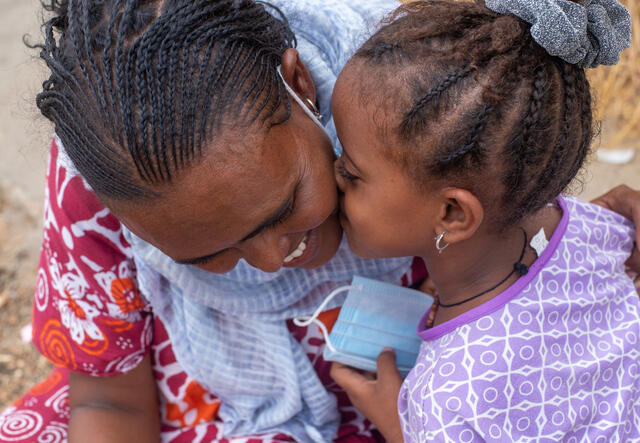 Azmera, 30, from Tigray, smiles as her young daughter kisses her cheek.