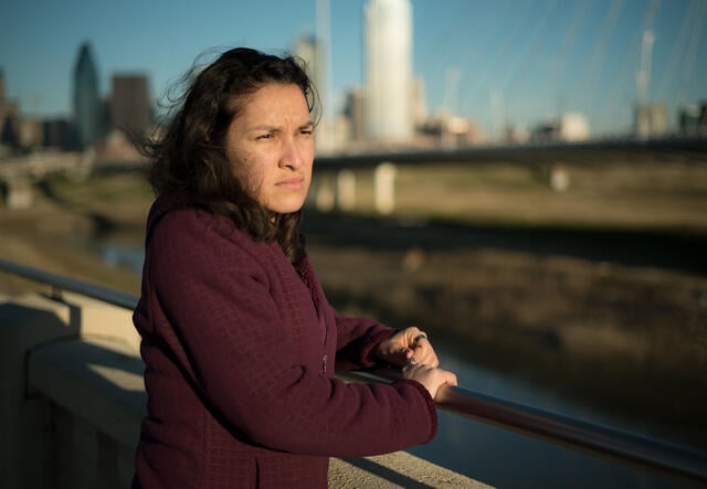 Valentina, una refugiada de El Salvador, se encuentra en un puente en Dallas, TX, y mira hacia el agua.