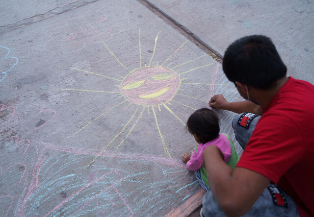 Un padre y su hijo dibujan con tiza. 