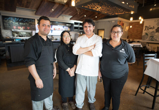 A chef stands with his staff in his restaurant.