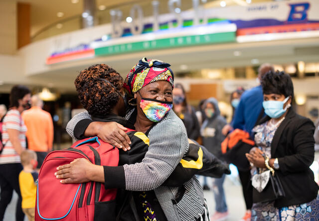 Two refugee women hug after being reunited in an airport.