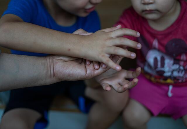 Abdul plays a game of stacking hands with his colleague's two young children.