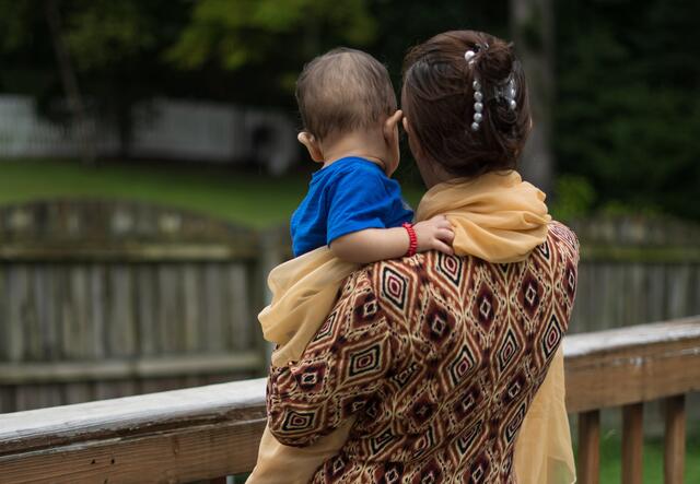 Afghan refugee Hadiya, 27, holds her yougest child as they look over a wooden fence at the home where they are staying in Virginia.