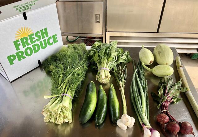 A box that says "FRESH PRODUCE" next to a variety of produce on a table.