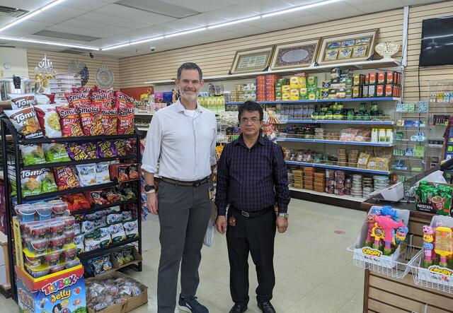 Justin Howell, Executive Director of the IRC in Atlanta, standing next to Baseer Basil, owner of Kabul Market, inside a store.