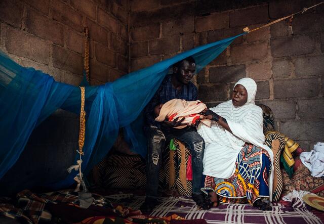 A Nigerian man and woman hold their baby.