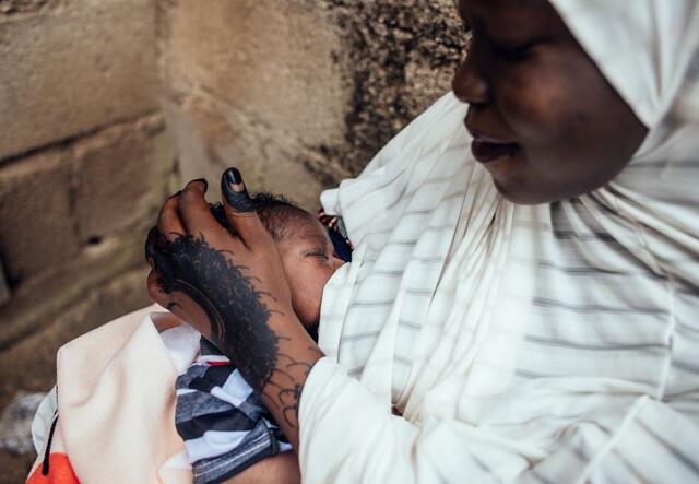 A Nigerian woman cradles the head of her baby.