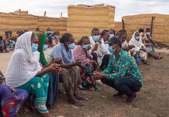 Människor på Tunaydbah flyktingläger i östra Sudan sitter på en bänk. 