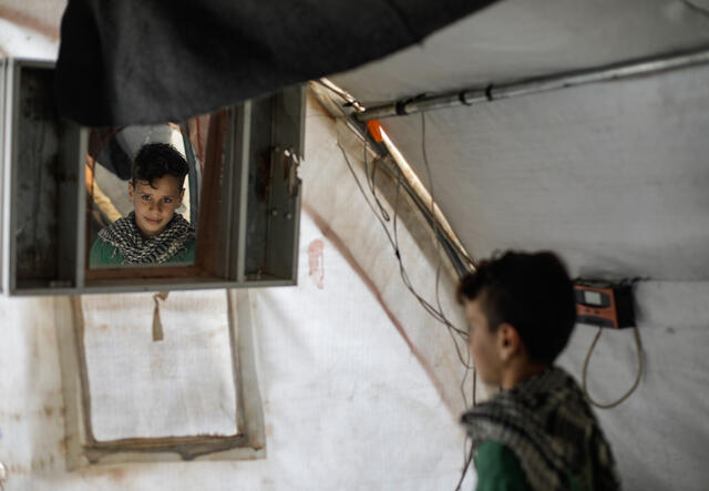Ten-year-old Omar looks at his reflection in a mirror in a tent. 