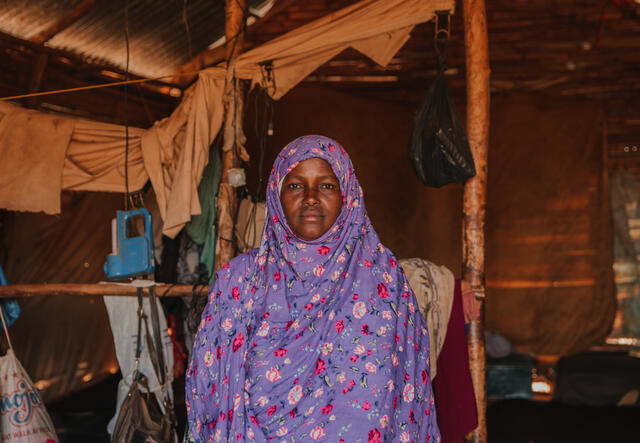 Halima poses for the camera inside a building made of wood.