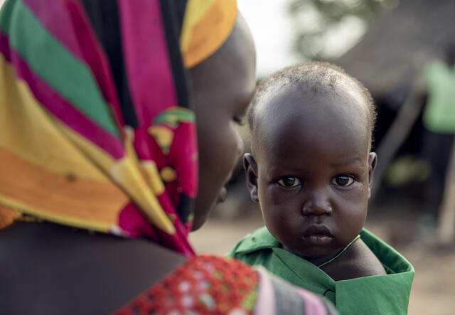Close up of a mother facing away from the camera while her baby faces toward the camera.