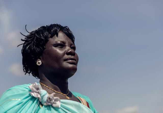 Against a blue sky, a woman looks into the distance. 