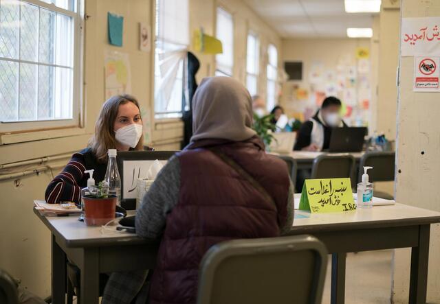 Two young women sit across from each other at a desk.