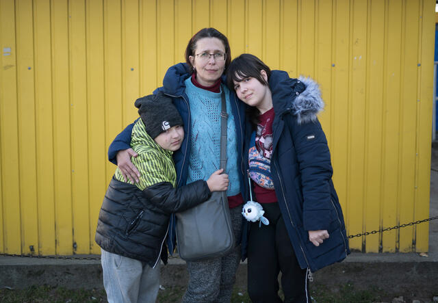 Marta looks at the camera with her arms around her two children. 