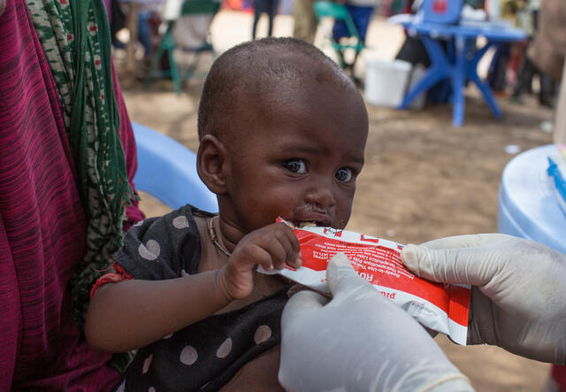 A Somali baby eats nutritious peanut paste from a packet at an IRC health clinic treating children for malnutrition..