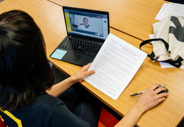 person sitting on the desk with a tax form on zoom with a client.