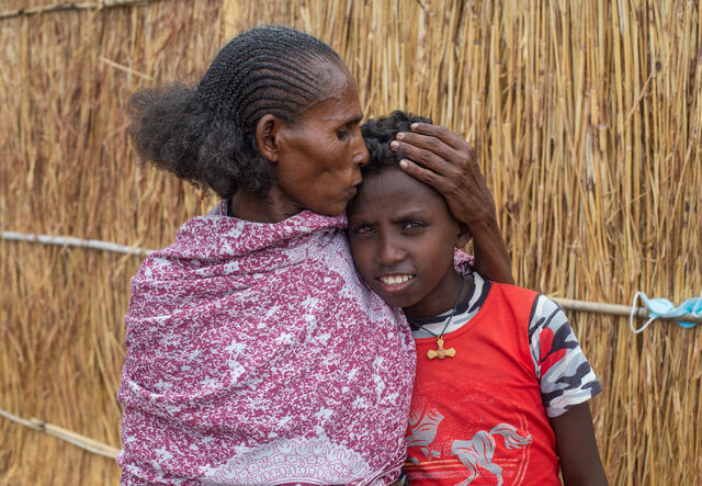 A mother kisses and holds the head of her young boy.