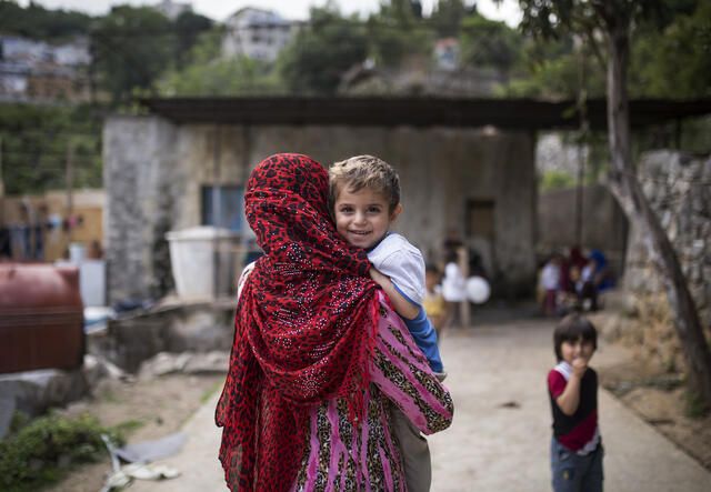 A Syrian mother in Lebanon carries her child