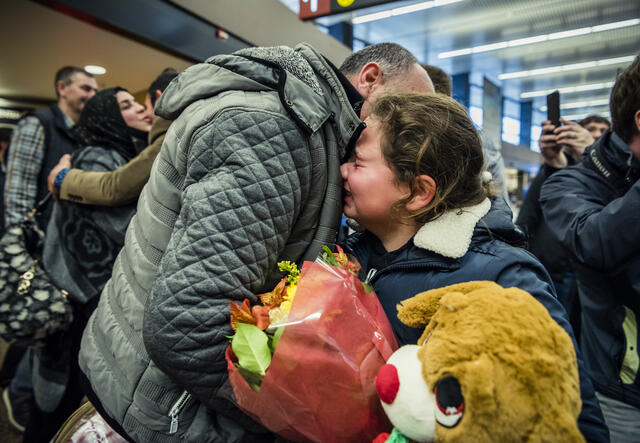 Syrian father and daughter embrace at a Seattle airport as their family is reunited