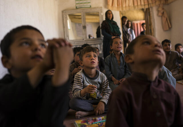 Boys sitting on the floor listen to their teacher in Afghanistan