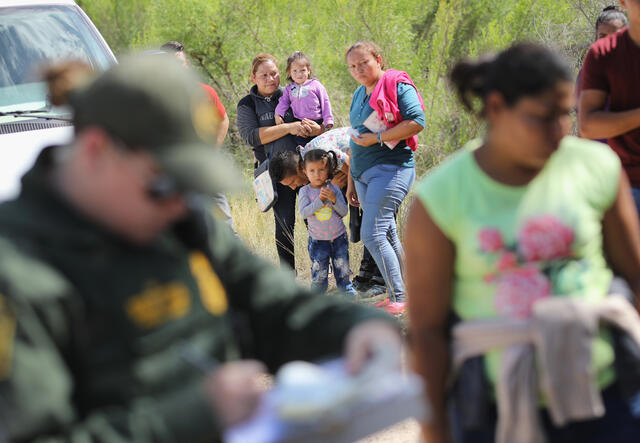 Central American asylum seekers wait as U.S. Border Patrol agents take groups of them into custody near McAllen, Texas.