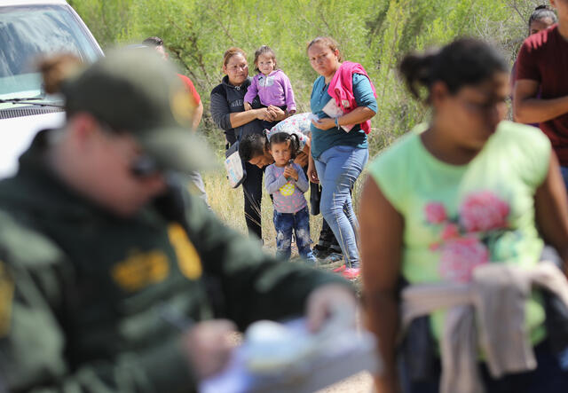 Central American asylum seekers wait as U.S. Border Patrol agents take groups of them into custody near McAllen, Texas. 