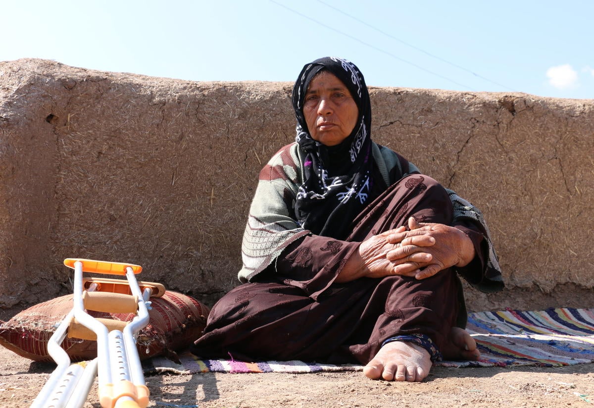 Miriam, 65, sits on a mat outside her home in Syria to get some fresh air