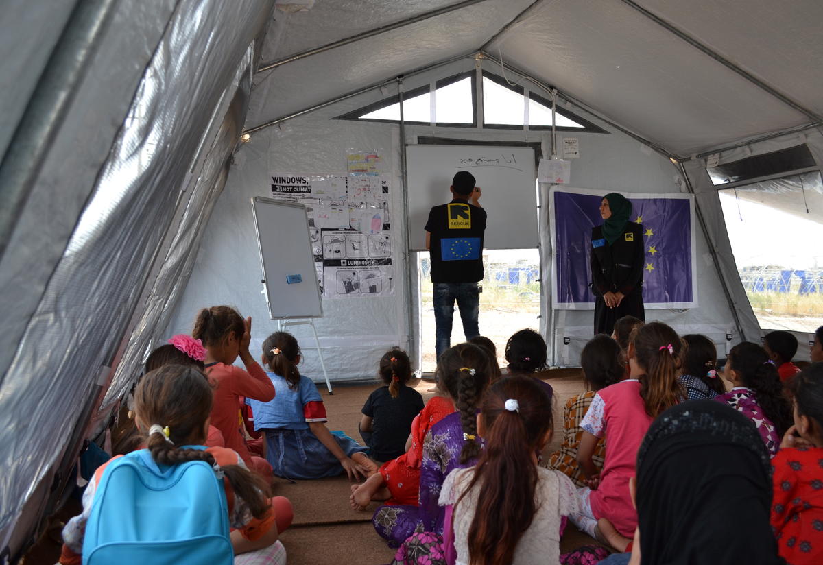Inside the IRC safe healing and learning space in Nargazilia camp. Two IRC aid workers lead a class in the tent that serves as a safe healing and learning space in Nargazilia camp.