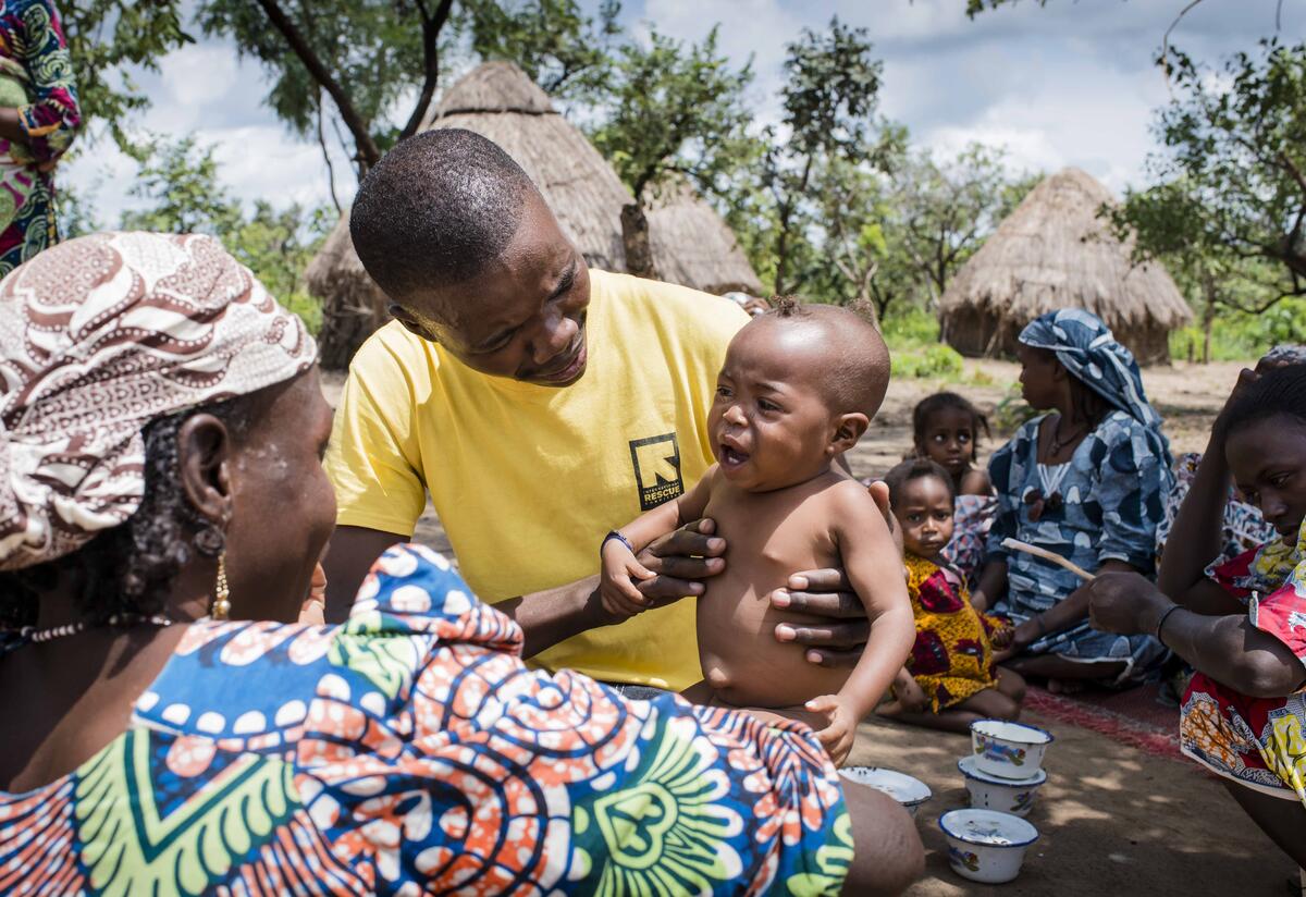 An IRC health worker examines children as people return to their village in the Central African Republic after fleeing fighting. An IRC health worker examines a young child suffering from malnutrition as people return to their village after fleeing fighting.