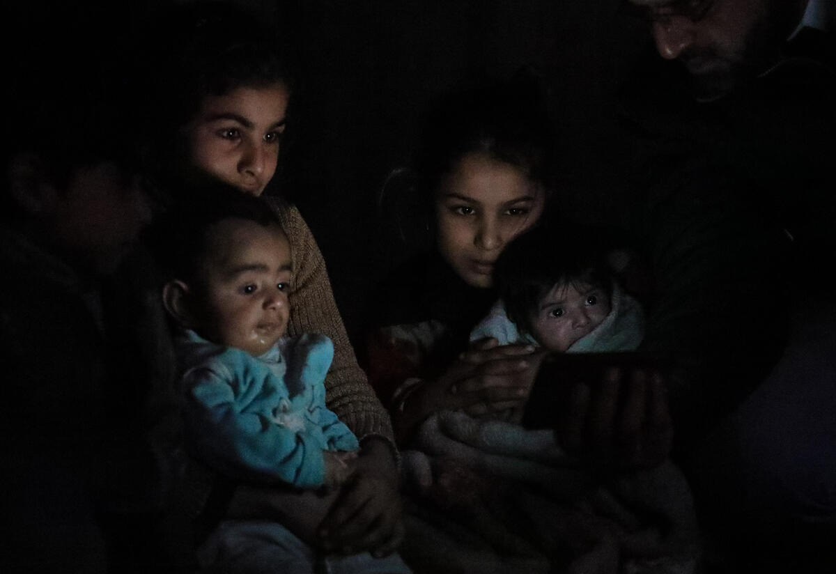A family huddles in the dark in their basement shelter in East Ghouta, Syria