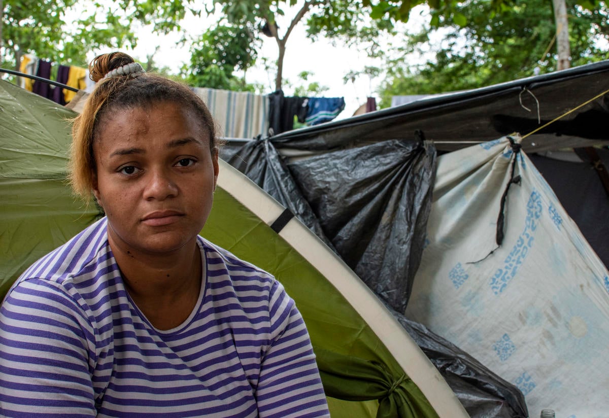 Angie, four months pregnant, sits outside her tent under a tree in Baranquilla.
