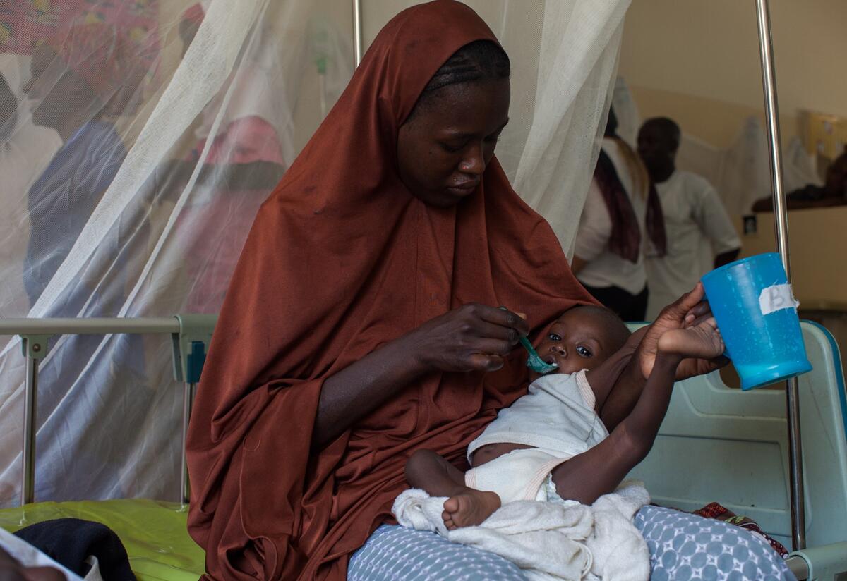 A mother feeds her malnourished baby therapeutic food with a spoon in an IRC health clinic in Nigeria.